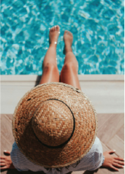 Vacationer wearing straw hat with feet in pool