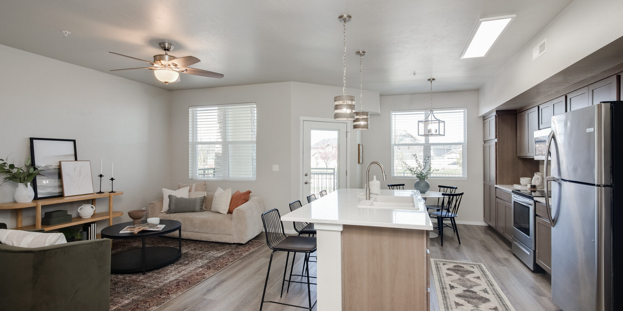 Modern open-concept kitchen and living area with stylish wood-look flooring. This CBH Homes space showcases durable and easy-to-maintain flooring, perfect for busy households. Learn more about flooring maintenance tips to keep your home looking fresh and beautiful.