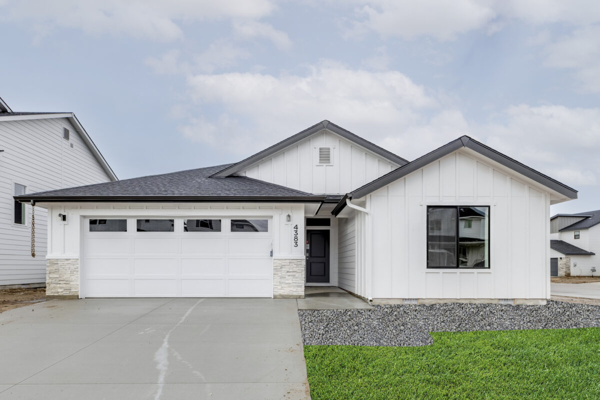 A modern white farmhouse-style home with a black roof, large front window, and two-car garage, set in a developing neighborhood. This home is an example of homes that are part of the upcoming Deer Valley community by CBH Homes, offering brand-new homes in a sought-after location. Stay tuned for more details on availability and home designs coming soon!