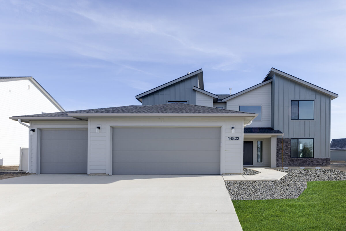Modern two-story home with a three-car garage in Centerville, Meridian, ID. Featuring a sleek gray and white exterior with large windows.