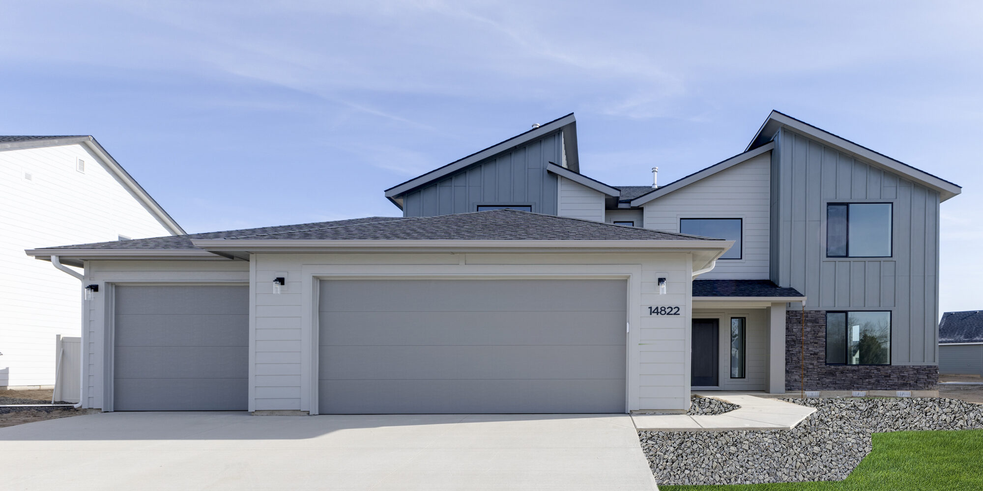 Modern two-story home with a three-car garage in Centerville, Meridian, ID. Featuring a sleek gray and white exterior with large windows.